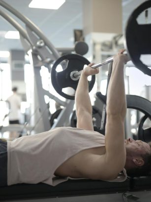Adult man performing bench press in a gym, focusing on strength and fitness.