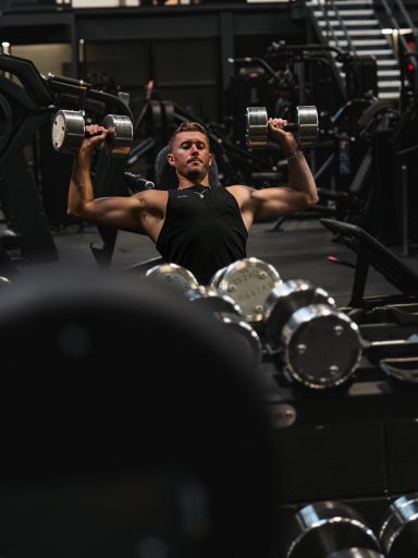 a man in a gym lifting a pair of dumbbells