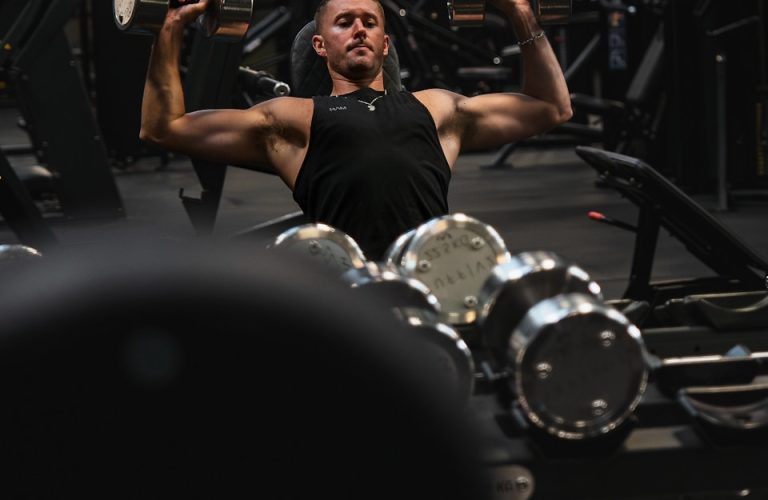 a man in a gym lifting a pair of dumbbells