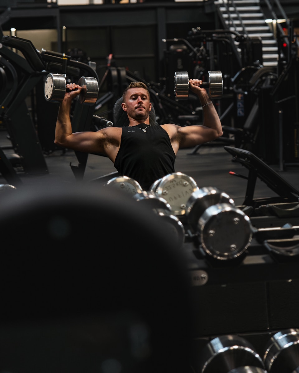 a man in a gym lifting a pair of dumbbells